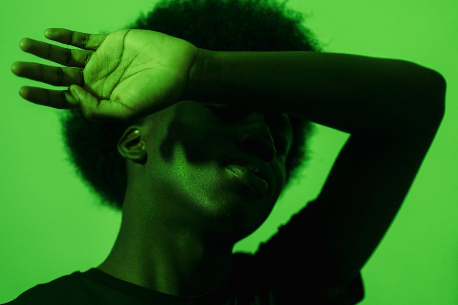 Dramatic portrait of a person with arm raised, set against a vibrant green backdrop.